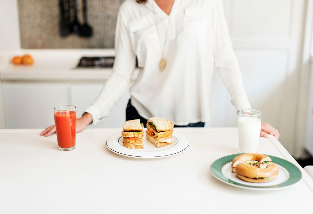 Sandwiches with juice and milk on white table in kitchen