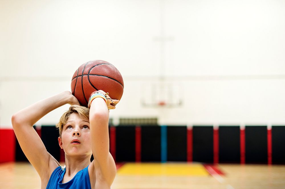 Young caucasian boy playing shooting basketball in stadium