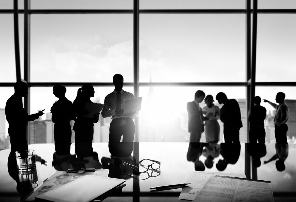 Group of business people discussing at sunrise reflected onto table with document.