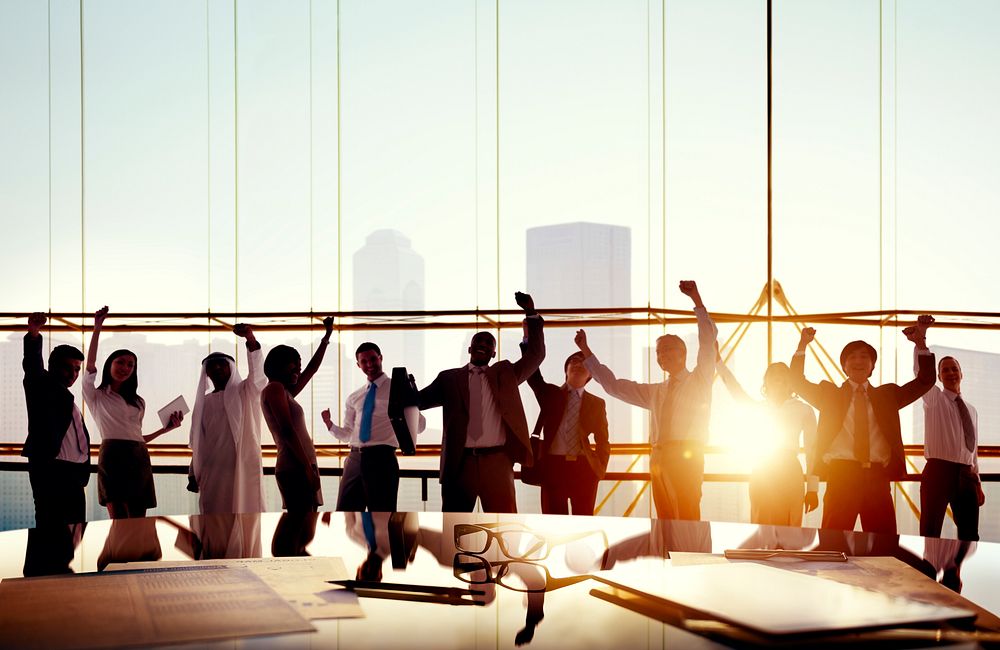 Group Of Business People With Their Arms Raised In Board Room