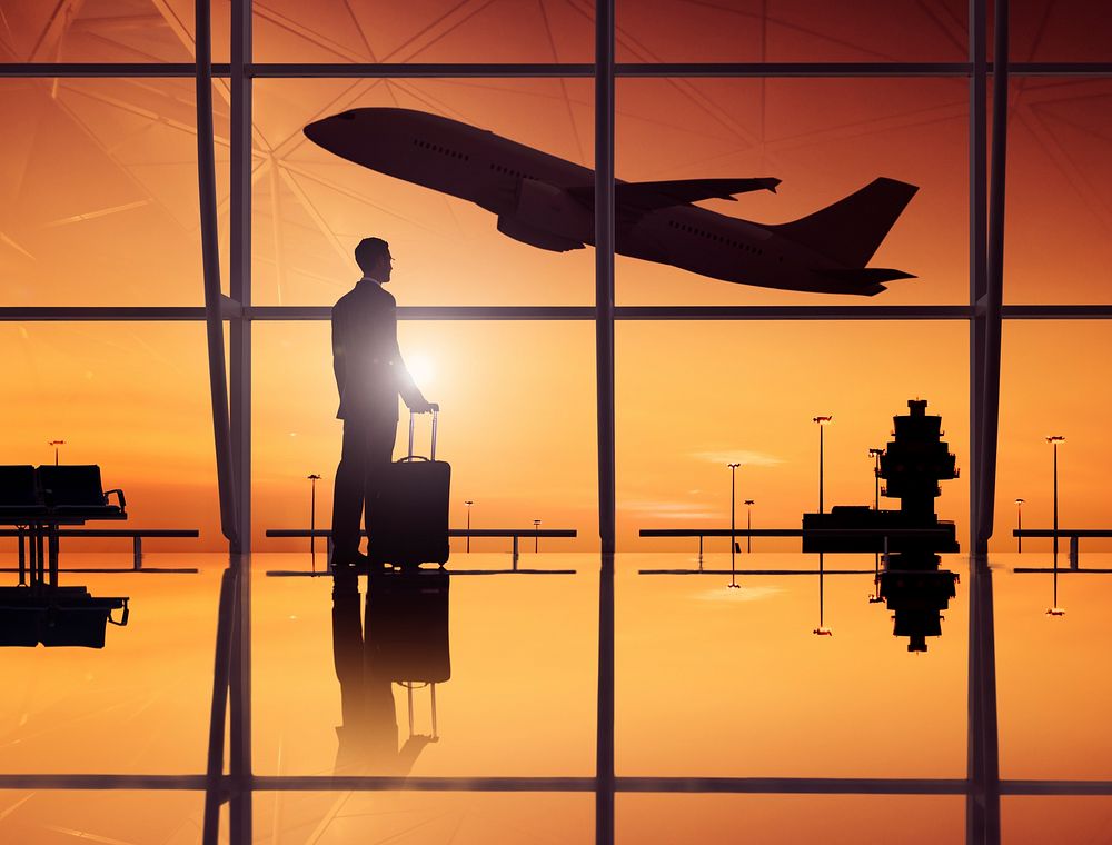 Businessman Waiting In An Airport Lounge With A Scenery Of Departing Airplane