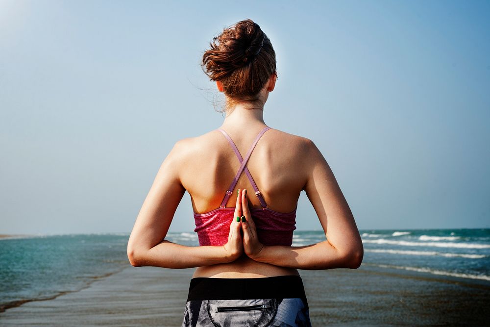 Woman doing reverse namaste yoga pose at the beach