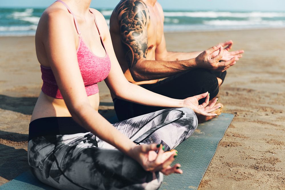 The couple is doing a yoga at the beach
