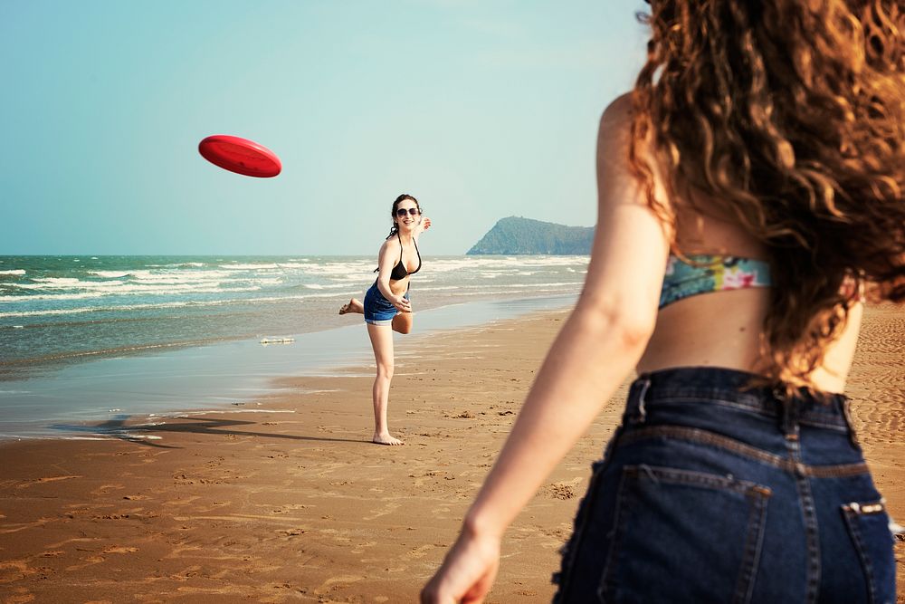 Women are playing frisbee at the beach