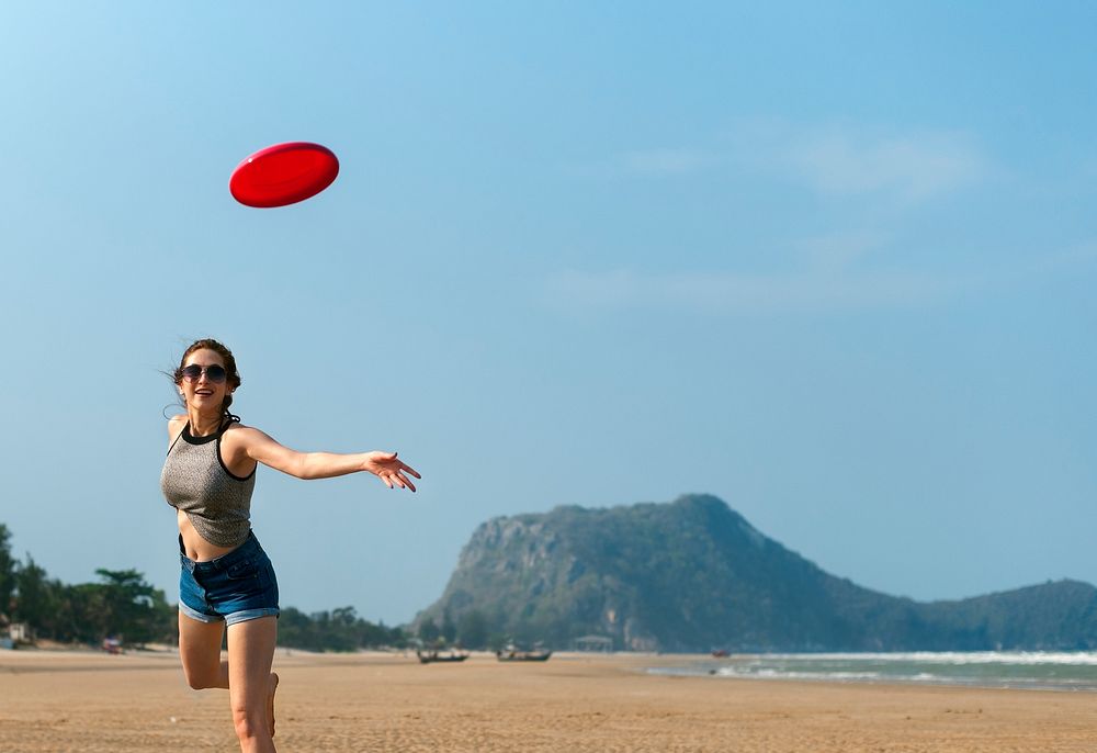 A woman is playing frisbee at the beach