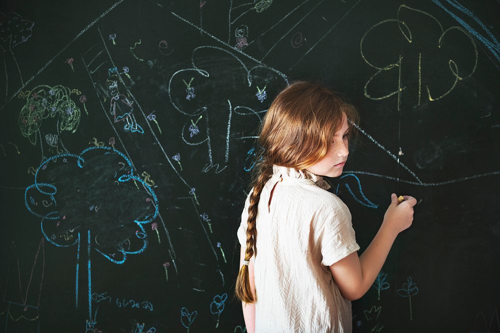 Young caucasian girl drawing on chalk board