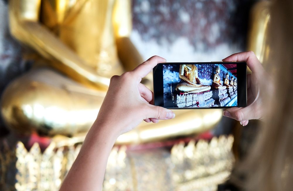 Tourist taking buddha statues by mobile phone