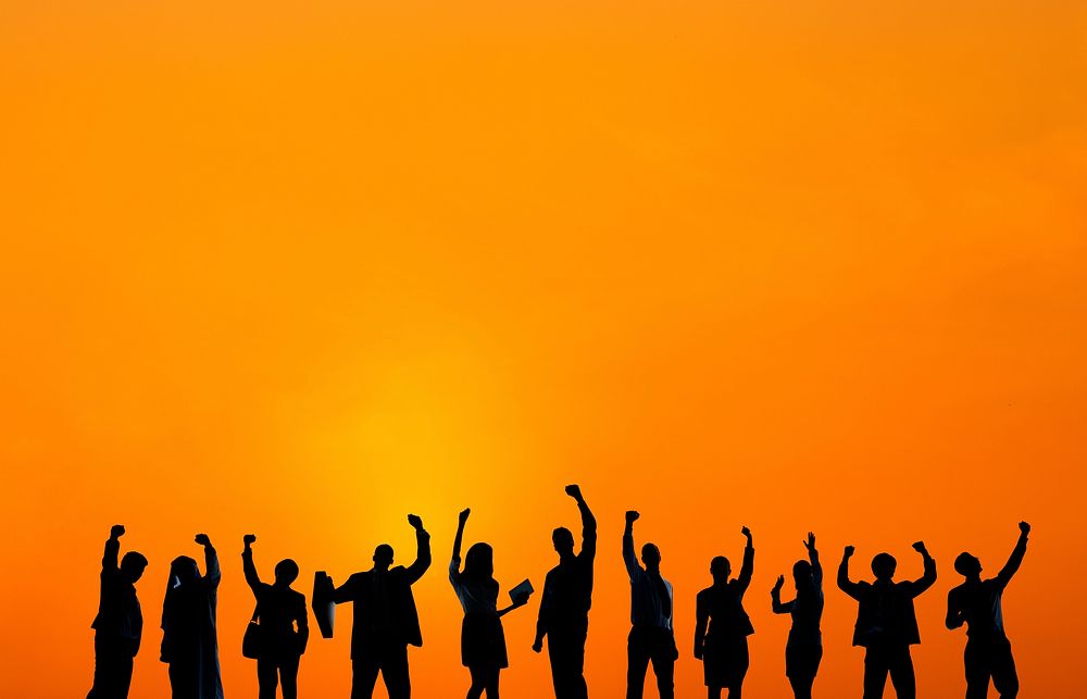Silhouette of business people with arms raise at sunset