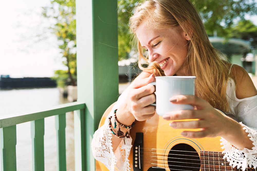 Blonde Girl Holding A Cup And Guitar By The Porch Concept