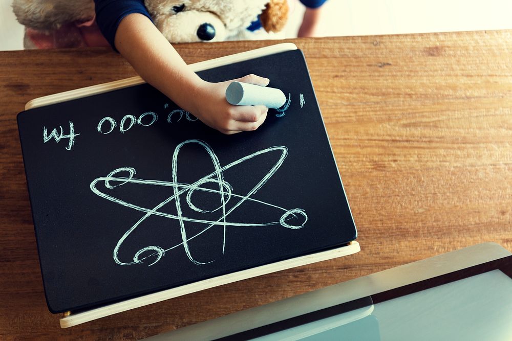 Aerial view of kid hand drawing on chalkboard