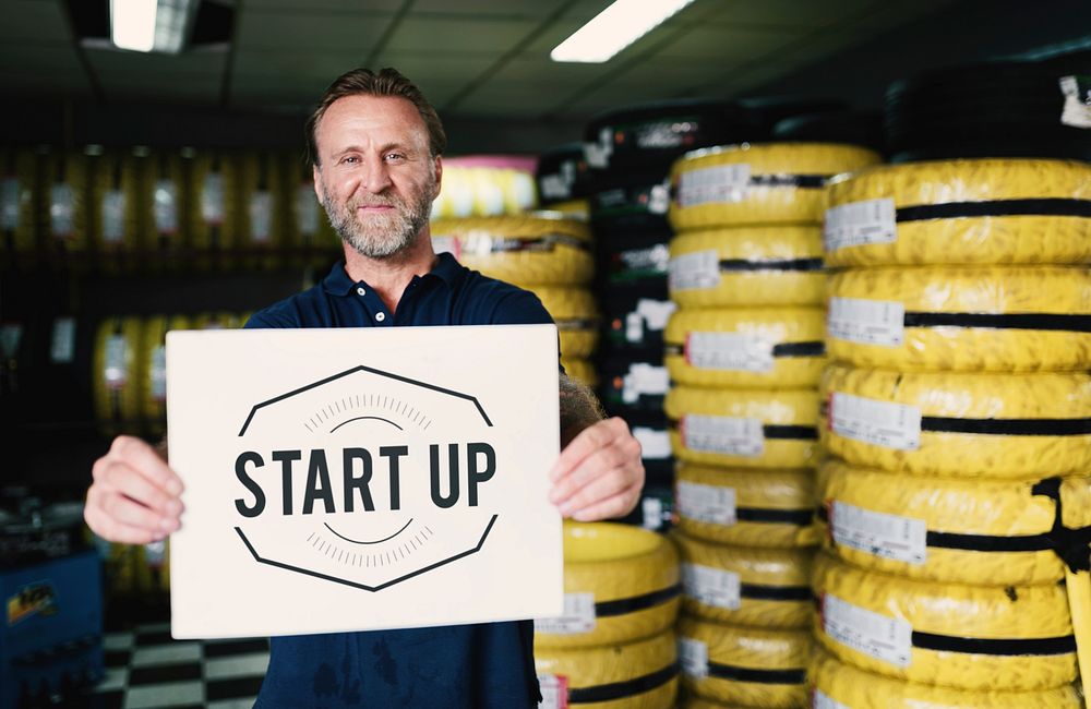 A mechanic holding a banner that says "Start up"