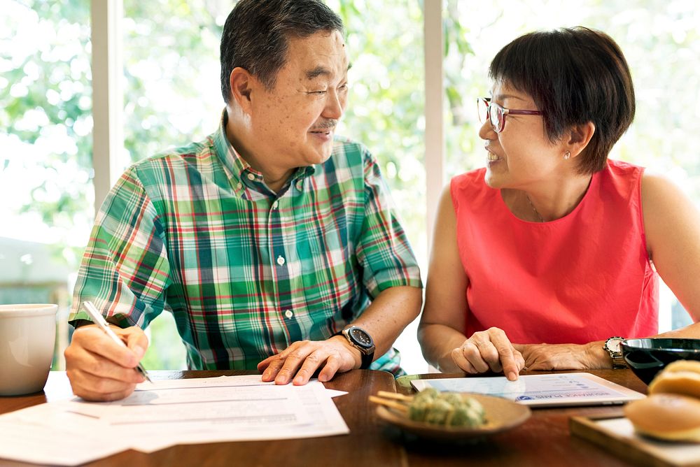 Senior Asian Couple Sitting Documents Tablet Concept