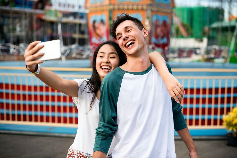 Cute couple taking a selfie at an amusement park
