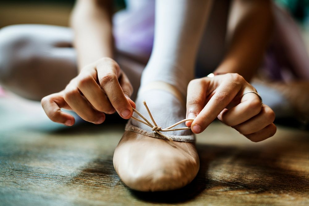 Closeup of girl tying a graceful bow on her ballet shoe
