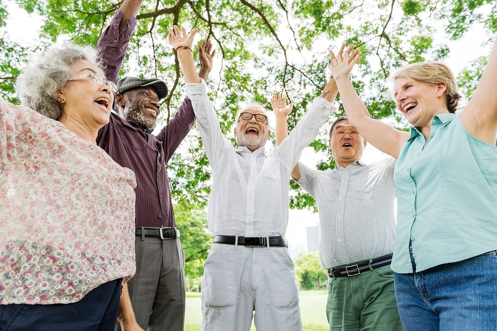 Group of happy retired senior friends  in the park cheering