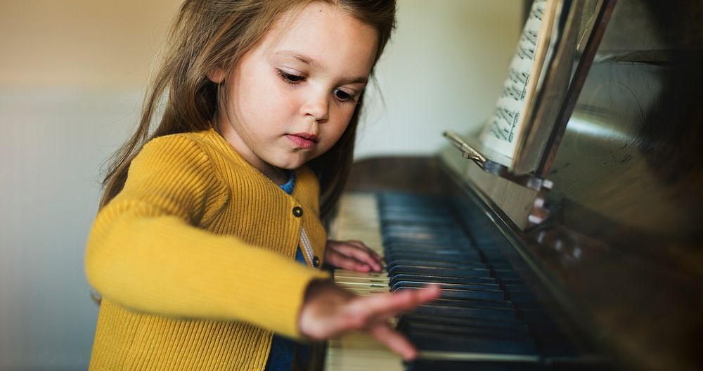 Cute and adorable little girl learning how to play a piano