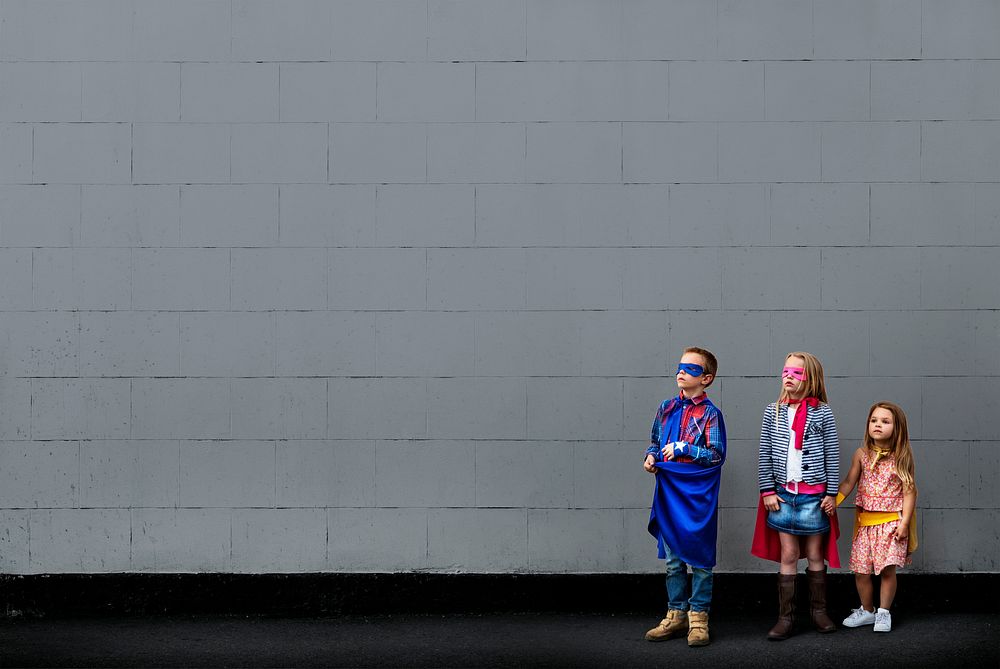 Kids in superhero costumes with blank wall