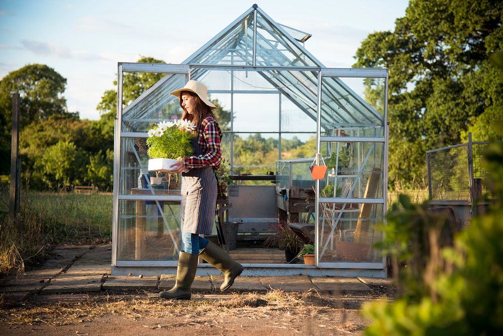 Young woman working at a glass greenhouse