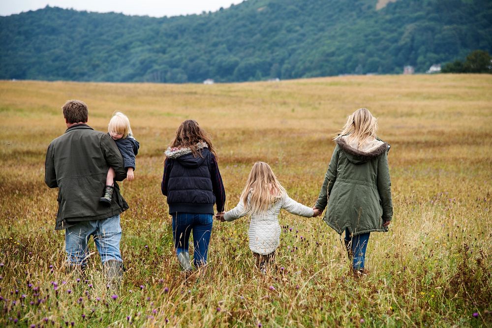 Rear view of family holding hands walking in a field