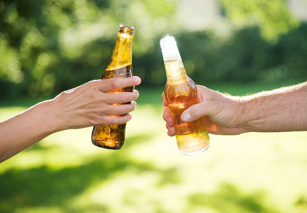 Closeup of hands clinging beer bottle together
