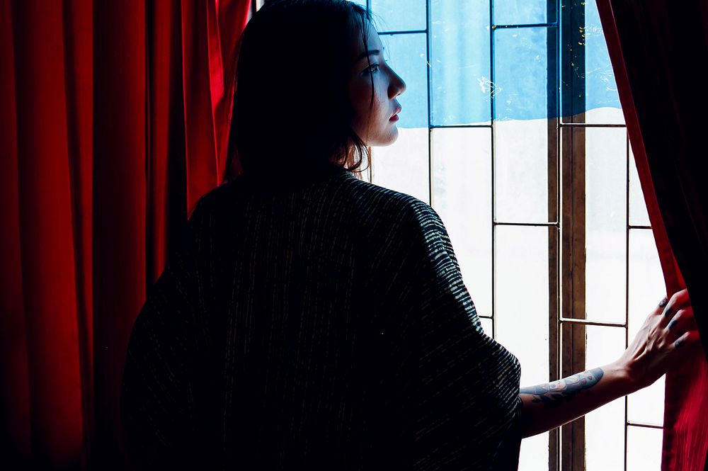 Rear view of asian woman standing by the window