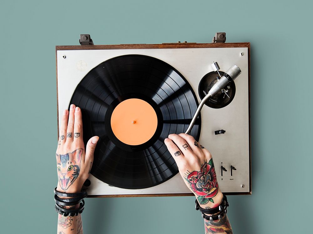 Tattooed hands playing on a vinyl turntable
