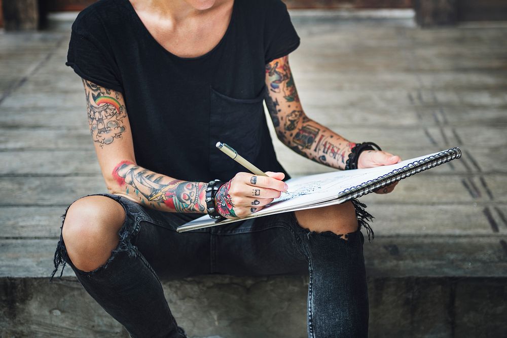 Tattooed woman sketching in a notebook
