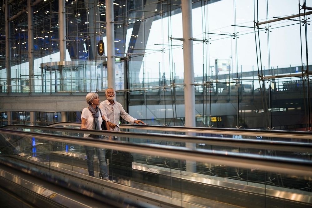 Senior couple traveling airport travelator scene