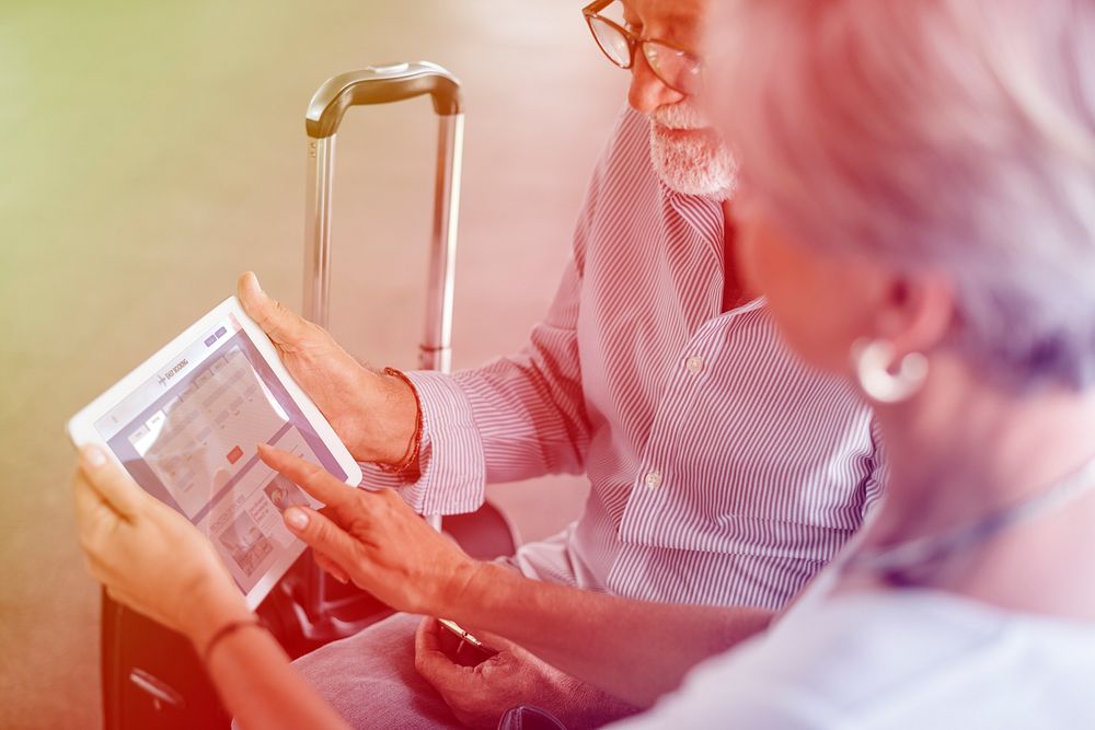 Senior adult couple checking boarding pass on digital tablet