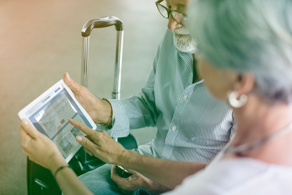 Senior adult couple checking boarding pass on digital tablet