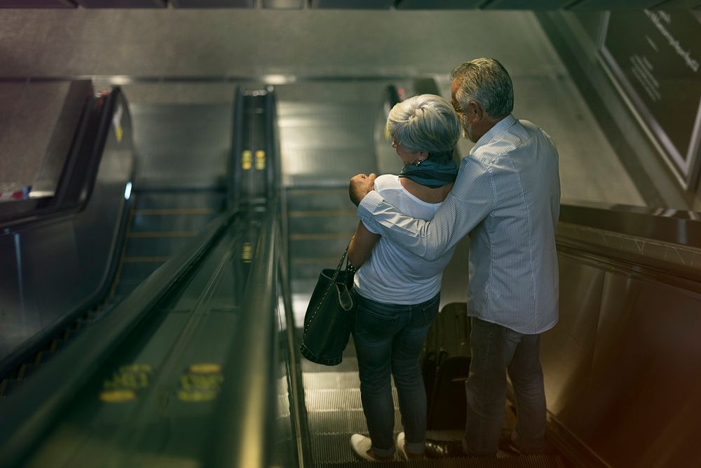Lovely senior couple tourists on escalator