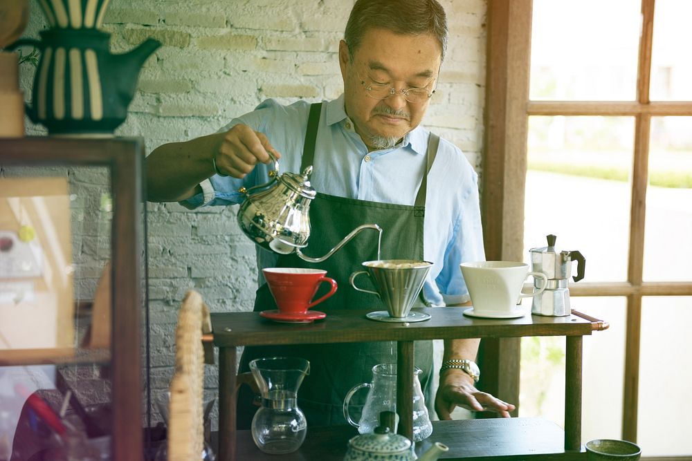 Senior adult man barista making coffee in cafe