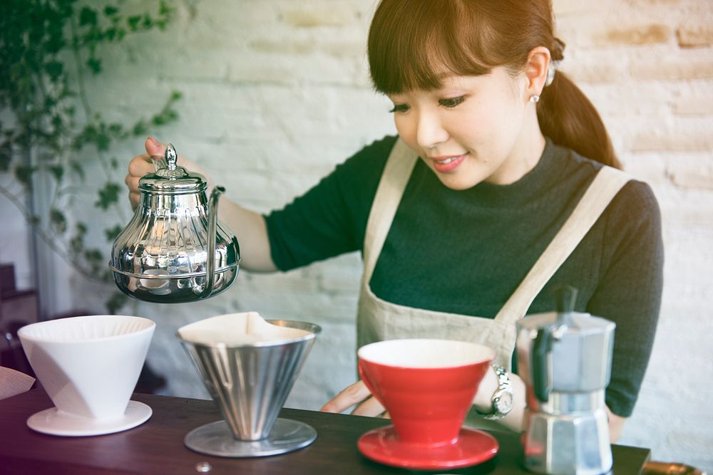 Young woman barista making coffee in cafe