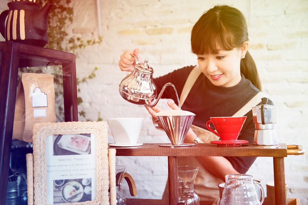 Young woman barista making coffee in cafe