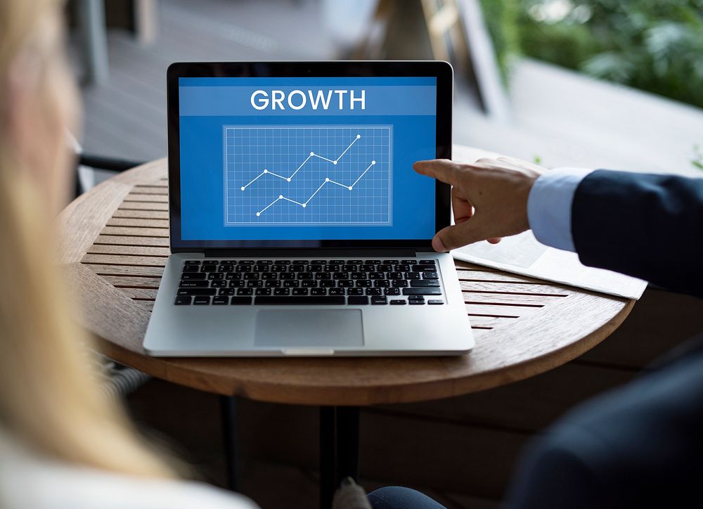 Businessman pointing to a laptop with the word, "GROWTH"