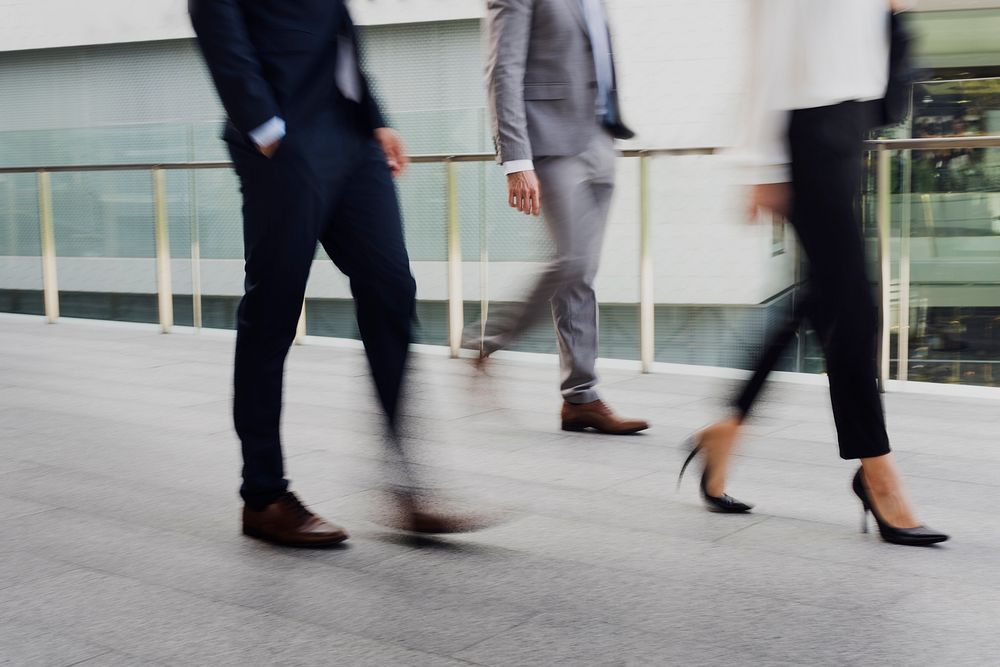 Businessmen and a businesswoman in suit walking in a city during rush hour