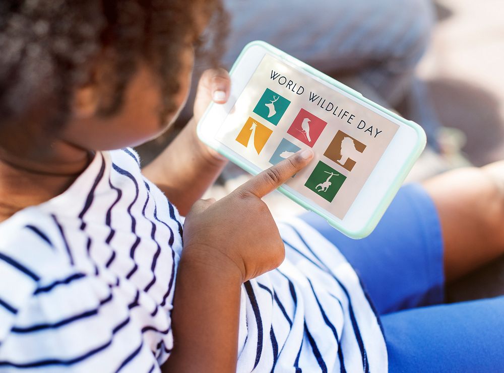 Girl playing on the tablet with save animals graphic
