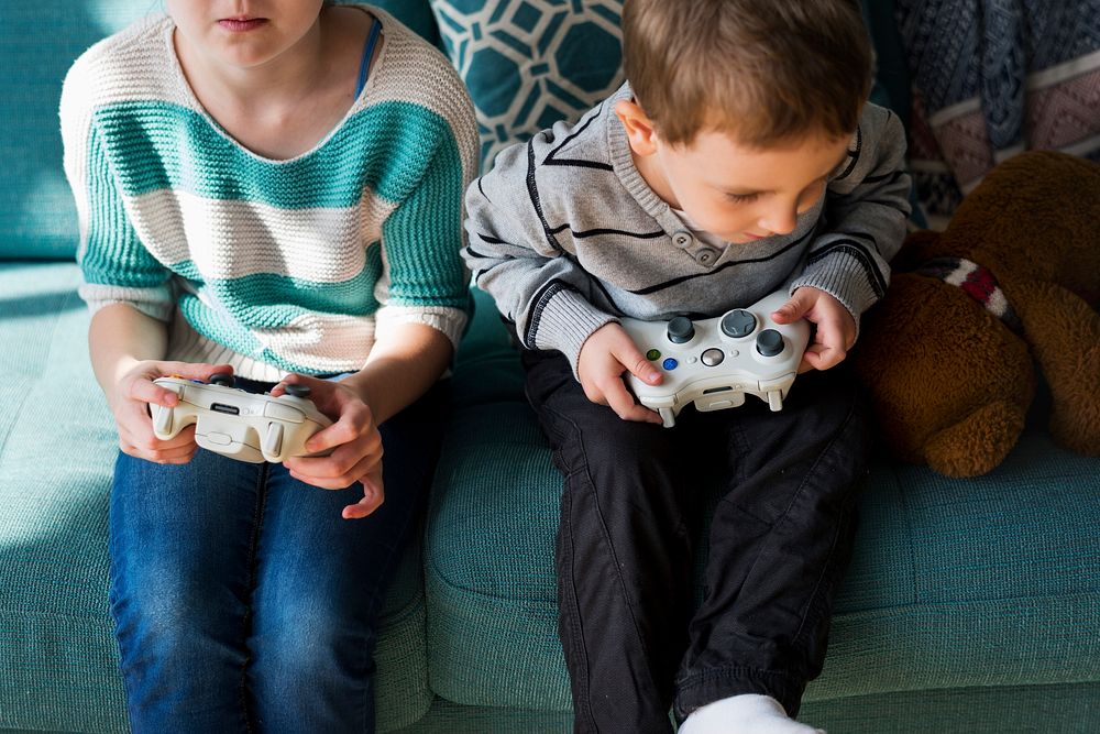 Brother and sister playing video game on a couch