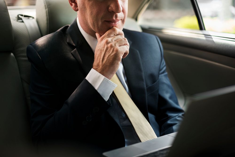 Businessman inside a car working on his laptop