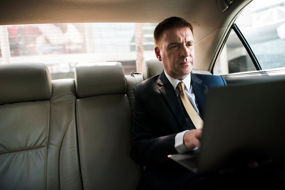 Businessman inside a car working on his laptop