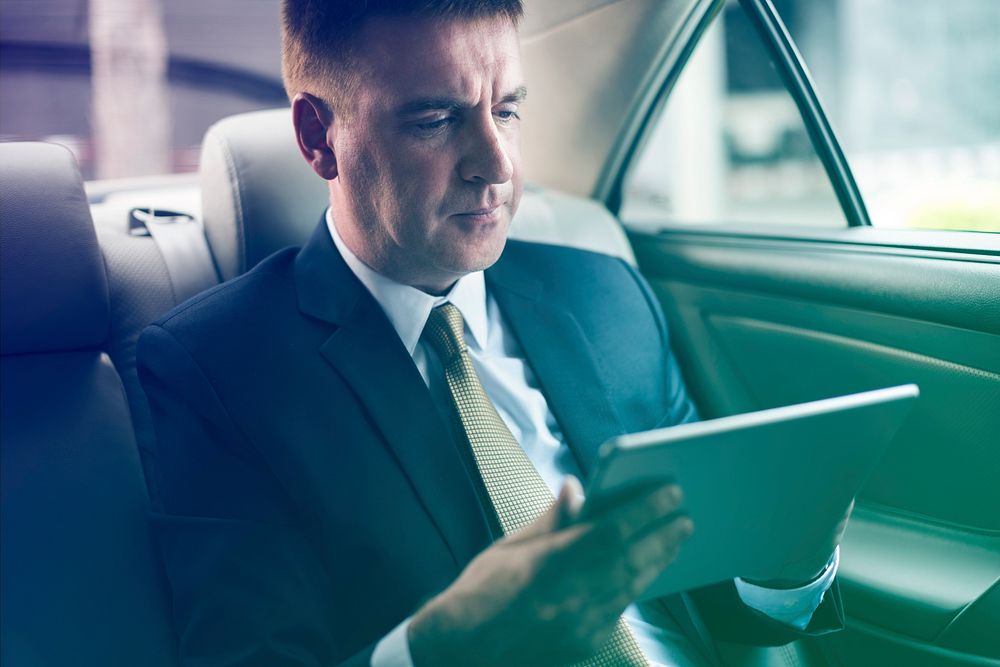 Businessman using digital tablet on backseat of the car