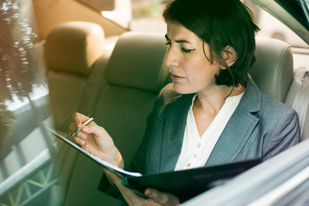 Businesswoman signing contract on backseat of the car