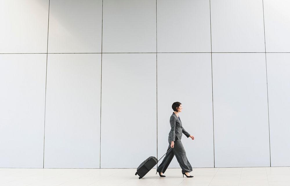 Businesswoman walking with her luggage in tow