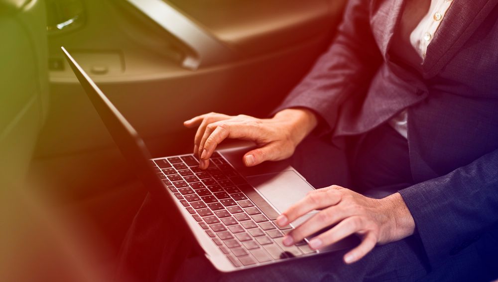 Businessman using laptop on backseat of the car