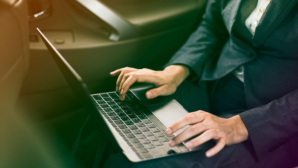Businessman using laptop on backseat of the car