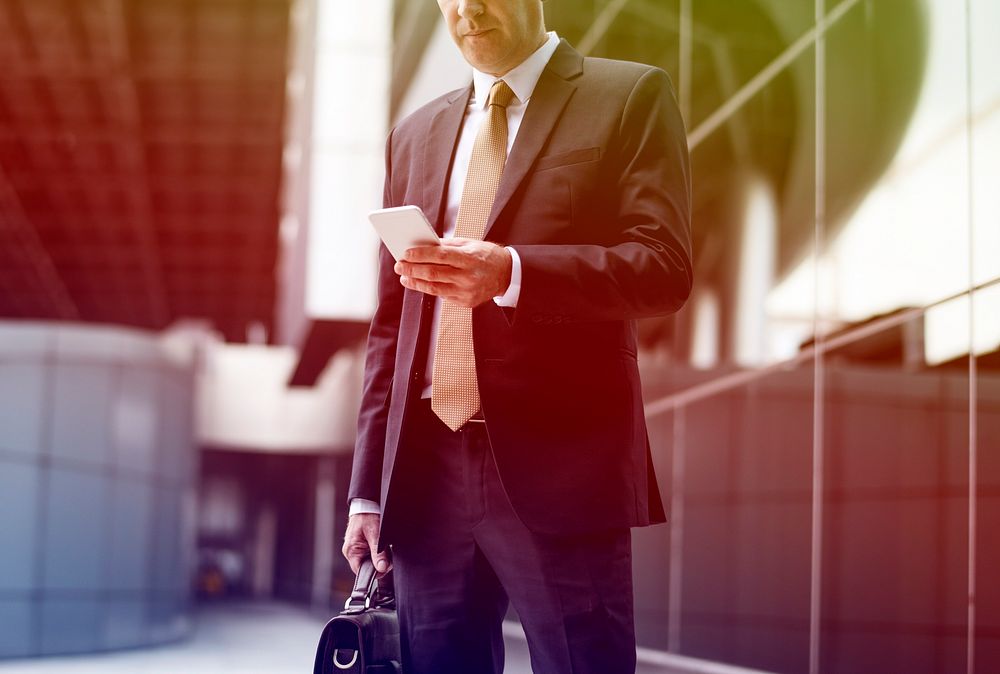 Businessman carrying briefcase and using mobile phone