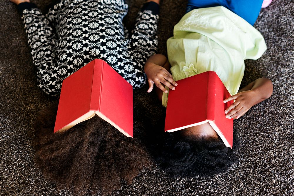 Two playful african children with books covered on their faces