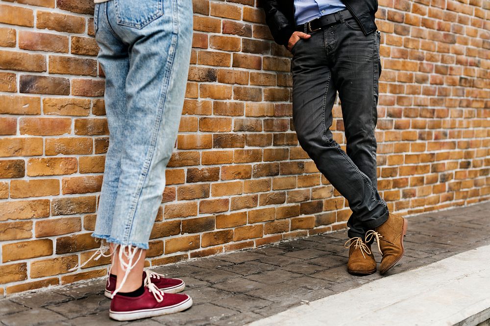 Man and woman leaning on a brick wall
