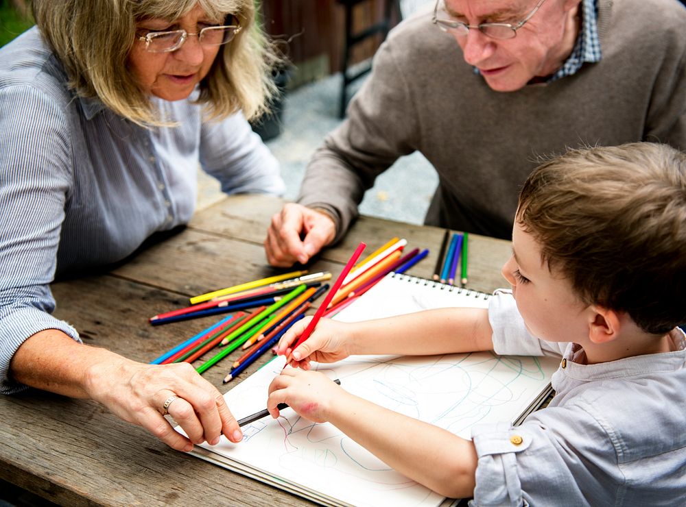 Young boy coloring with his grandparents