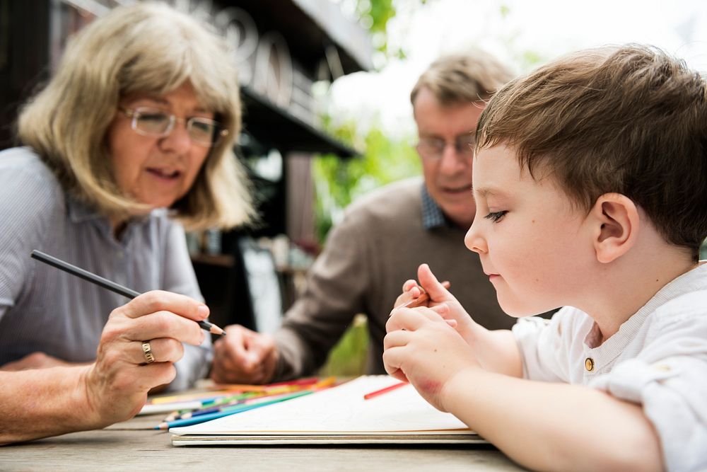 Grandparents helping young boy with coloring  book